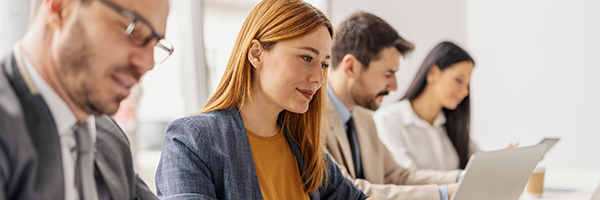 Businesswoman typing on a laptop during meeting at boardroom with her leadership team.
