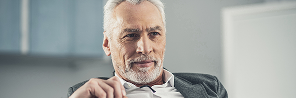 Glasses in hand. Handsome smart skillful businessman holding glasses in his hand while spending time in the office