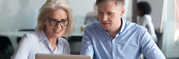 Businesswoman typing on a laptop during meeting at boardroom with her leadership team.