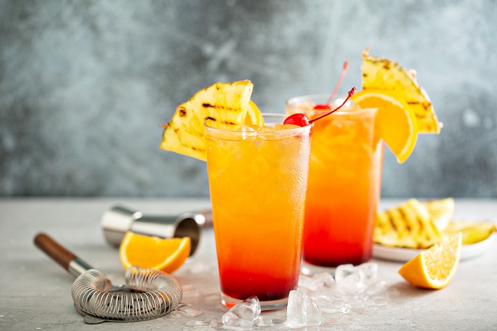 Tequila sunrise cocktail with grilled pineapple and orange